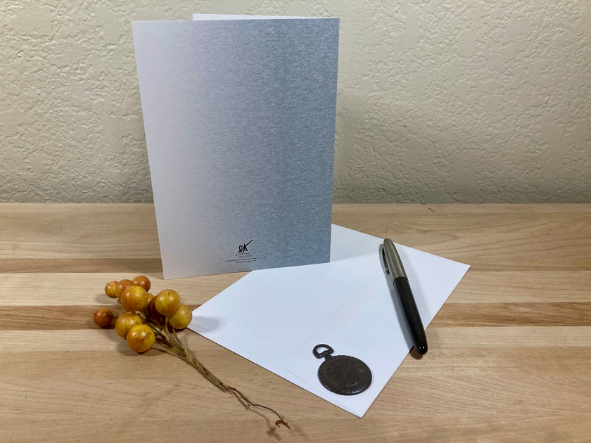 Greeting card, pen, and decorative elements on a wooden surface with a neutral background