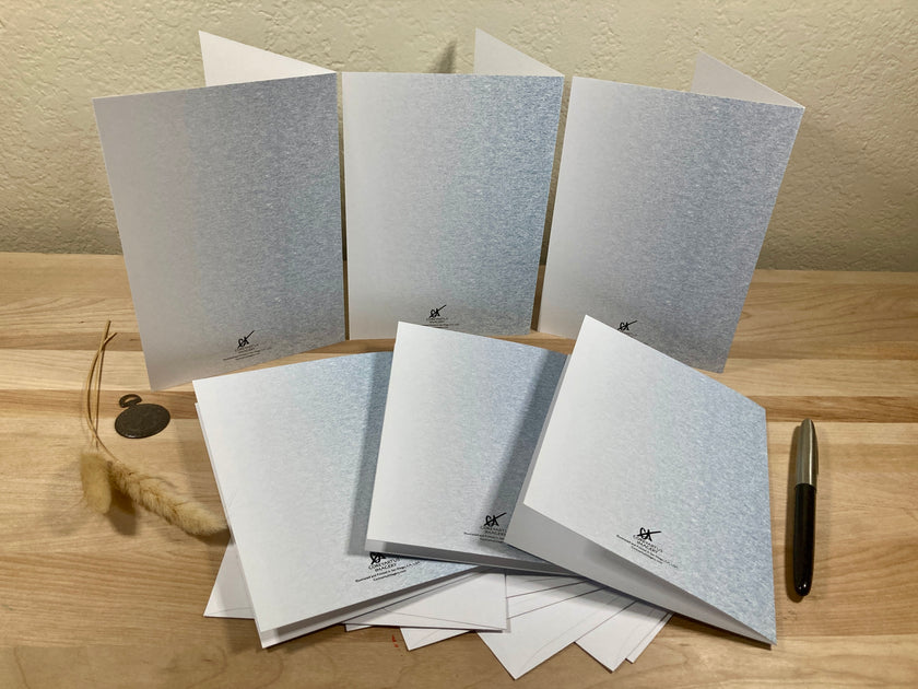 Set of gray greeting cards on a wooden surface with a pen.