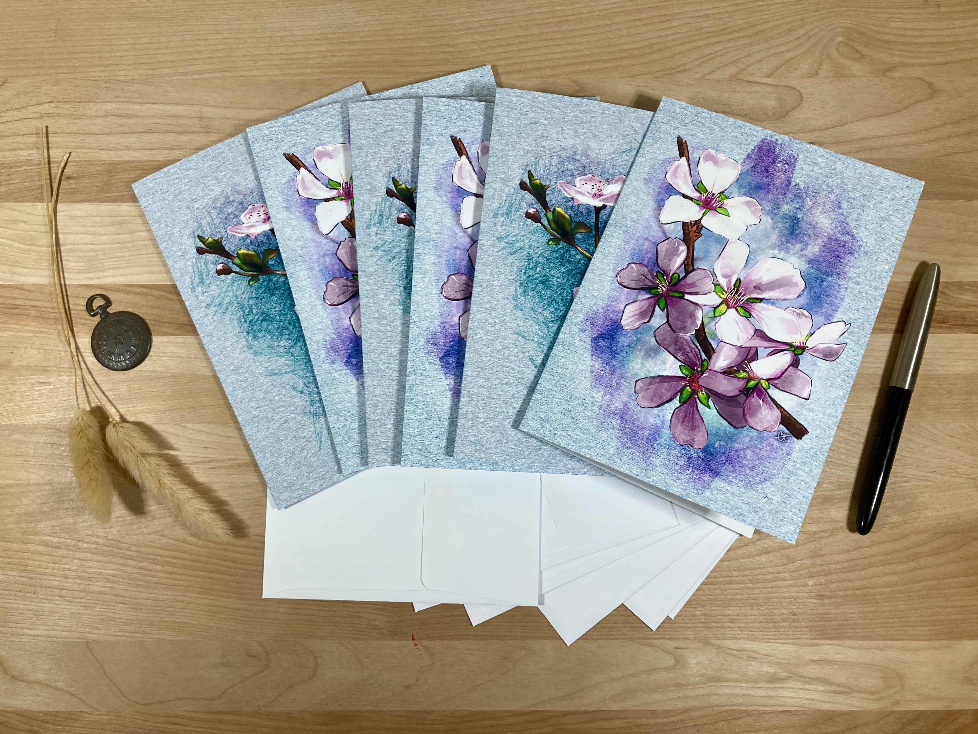 Set of floral greeting cards with matching envelopes on a wooden surface.