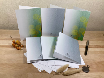 Set of greeting cards and envelopes on a wooden surface with decorative items.