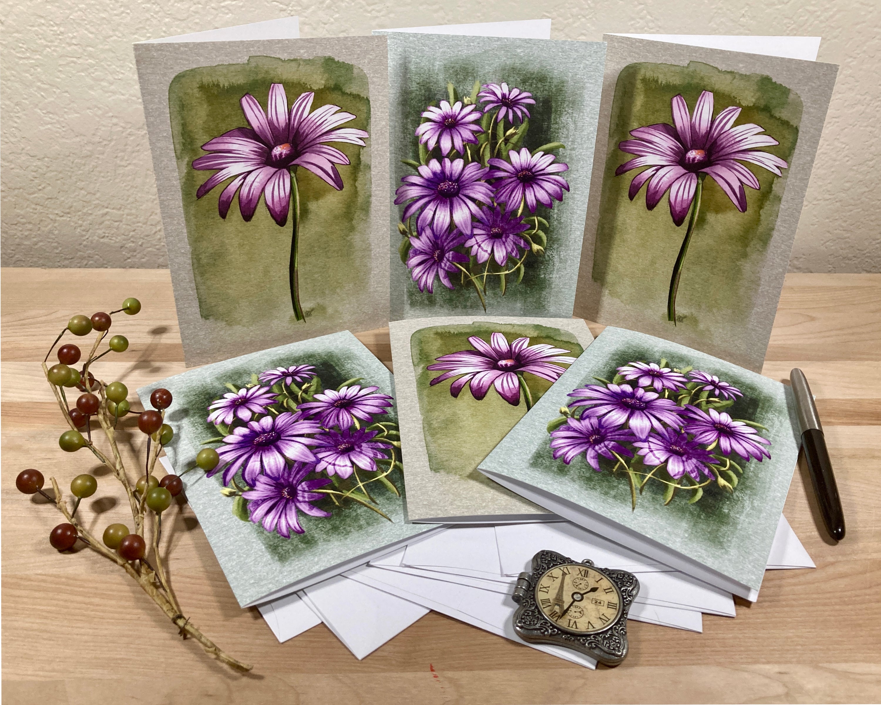 Set of greeting cards with purple flowers on a wooden surface with a pen and decorative elements.