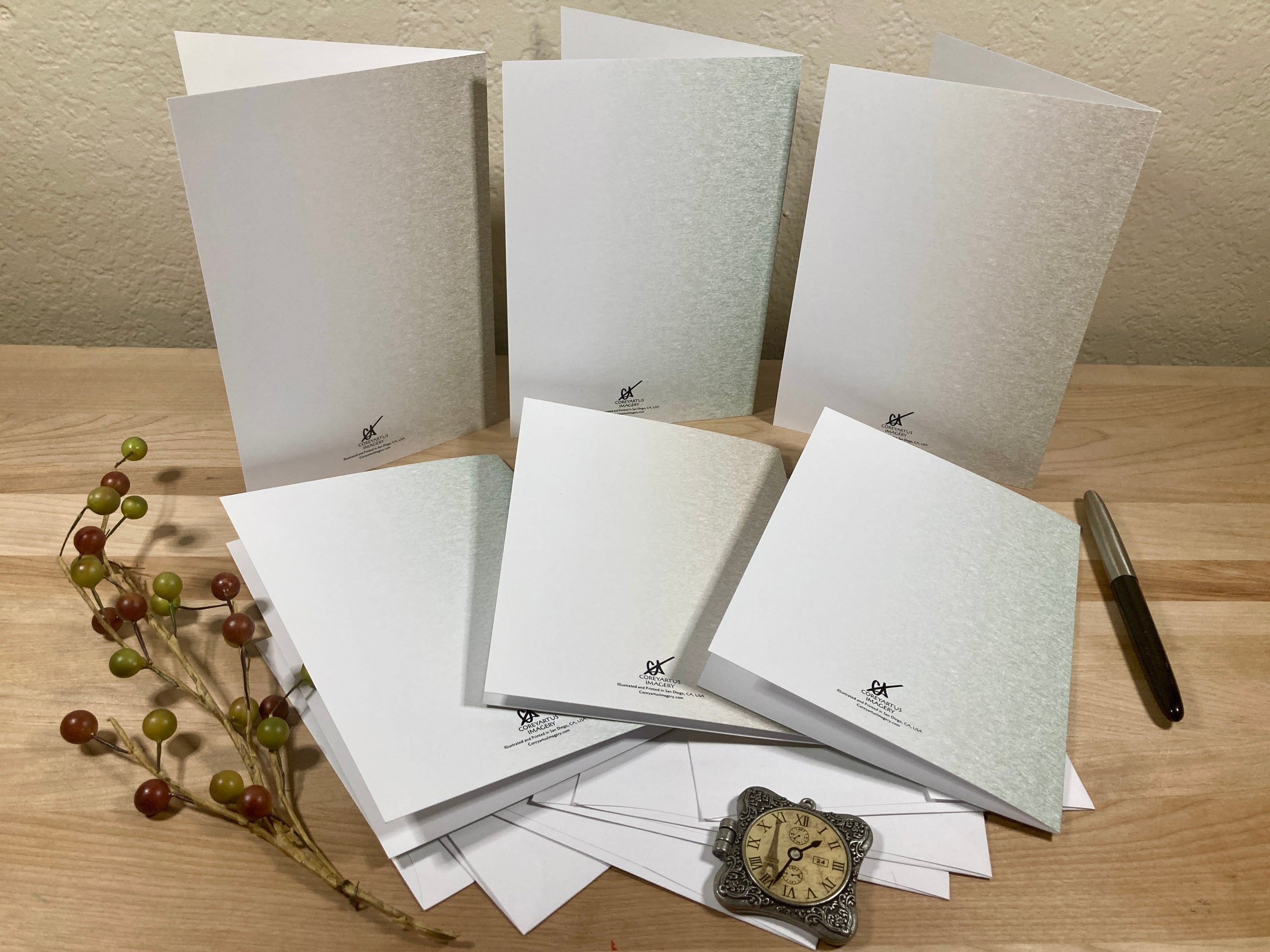 Set of white greeting cards with a pen and decorative items on a wooden surface