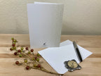 White greeting card with a pen and decorative branch on a wooden surface