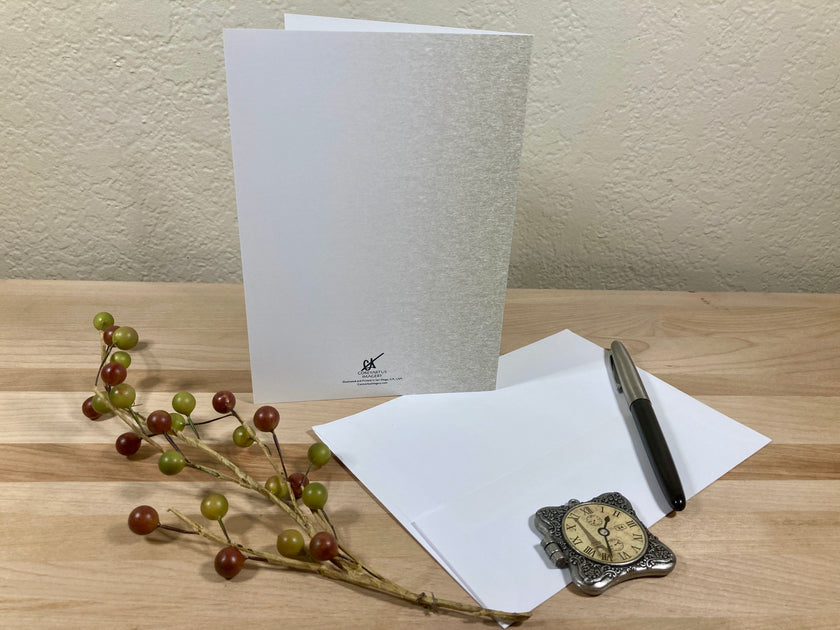 White greeting card with a pen and decorative branch on a wooden surface