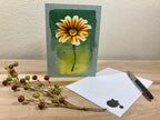 Greeting card with a sunflower design on a wooden surface with decorative elements.