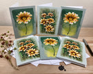 Set of six floral greeting cards on a wooden surface with a pen and small plant.
