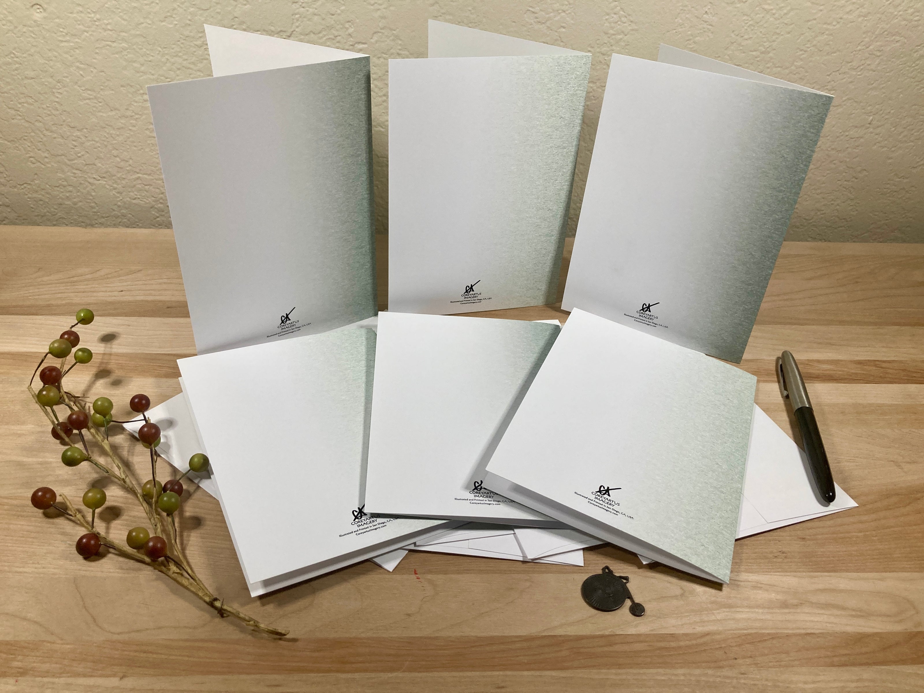 Backside of six greeting cards with a pen on a wooden surface
