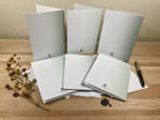 Backside of six greeting cards with a pen on a wooden surface