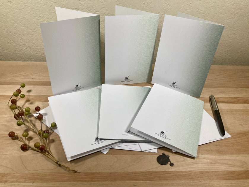 Backside of six greeting cards with a pen on a wooden surface