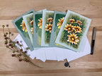 Set of greeting cards with floral design on a wooden surface
