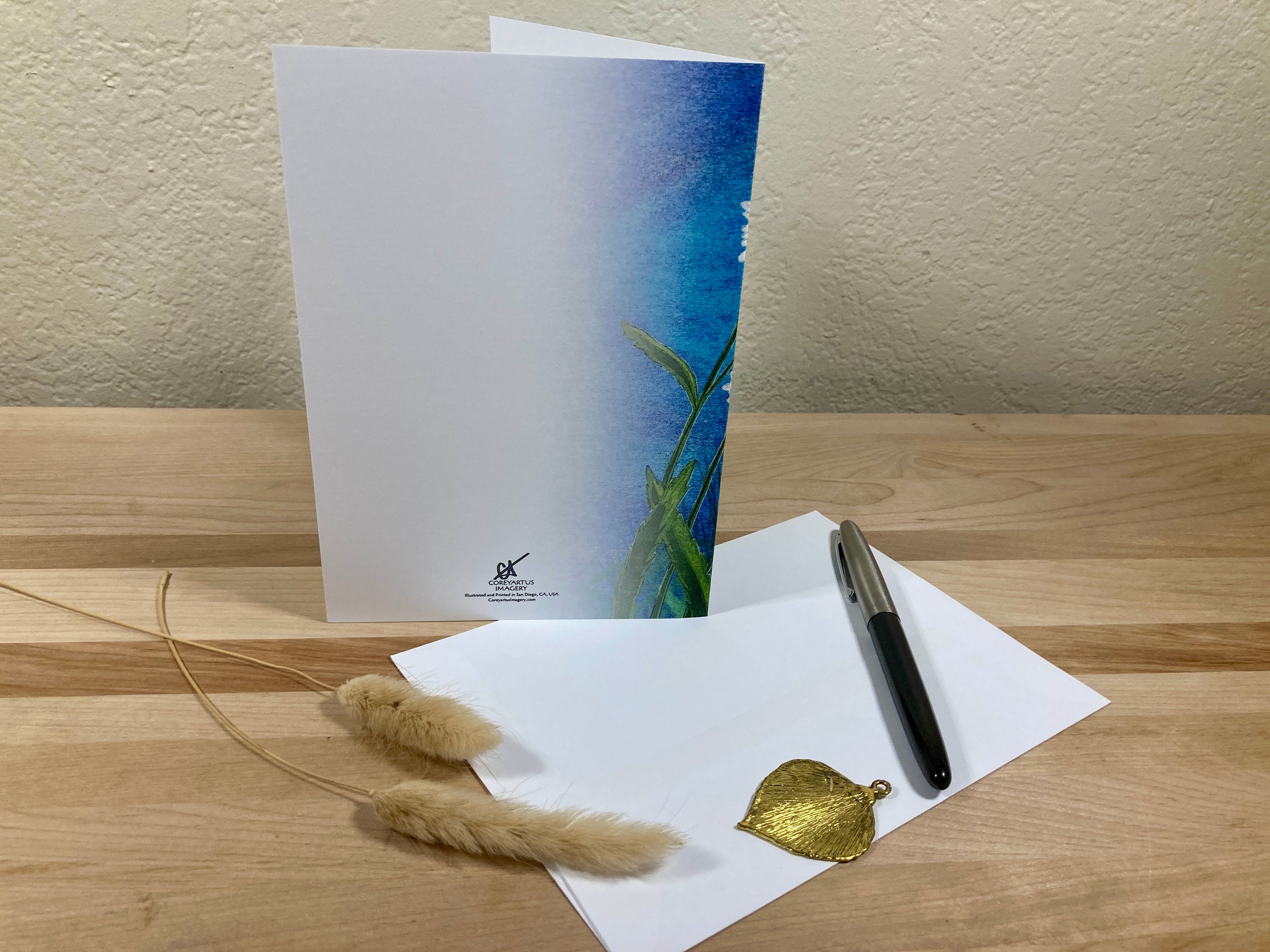 Greeting card, pen, and decorative elements on a wooden surface