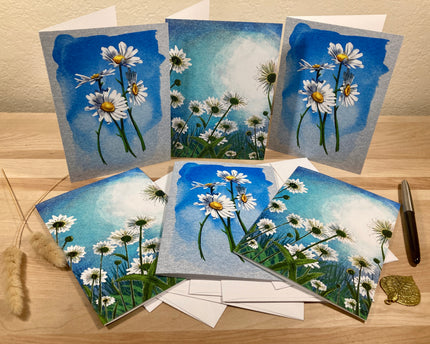 Set of greeting cards with floral designs on a wooden surface.