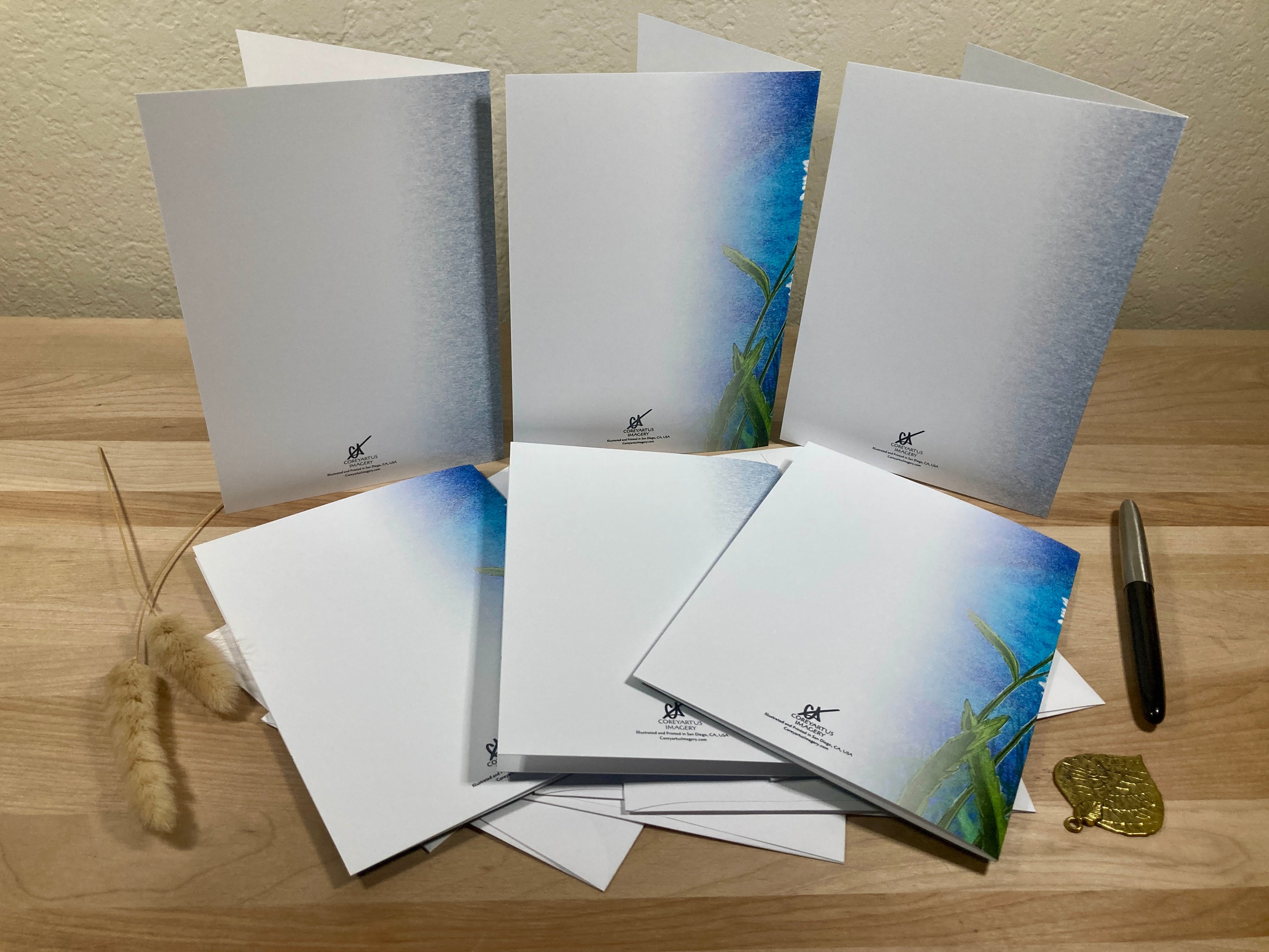 Set of greeting cards with nature-themed designs on a wooden surface