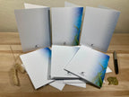 Set of greeting cards with nature-themed designs on a wooden surface