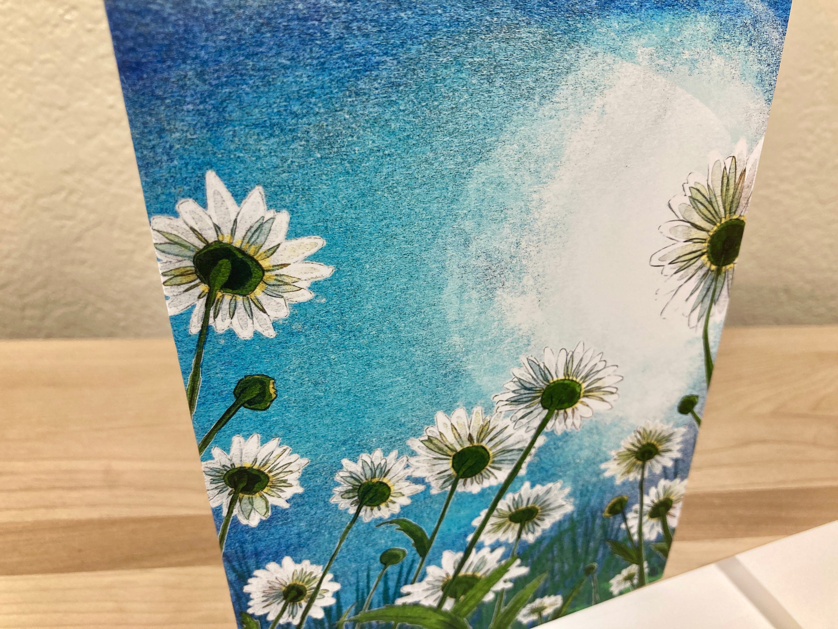 Card with daisy flowers against a blue sky background