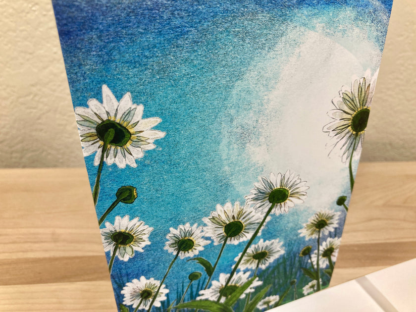 Card with daisy flowers against a blue sky background