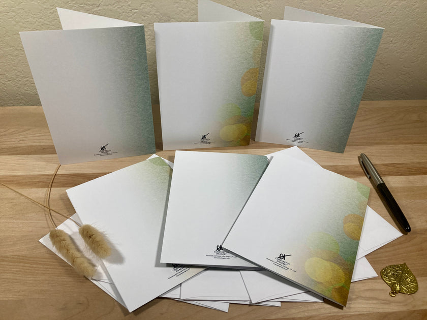 Set of stationery items including envelopes and a pen on a wooden surface.