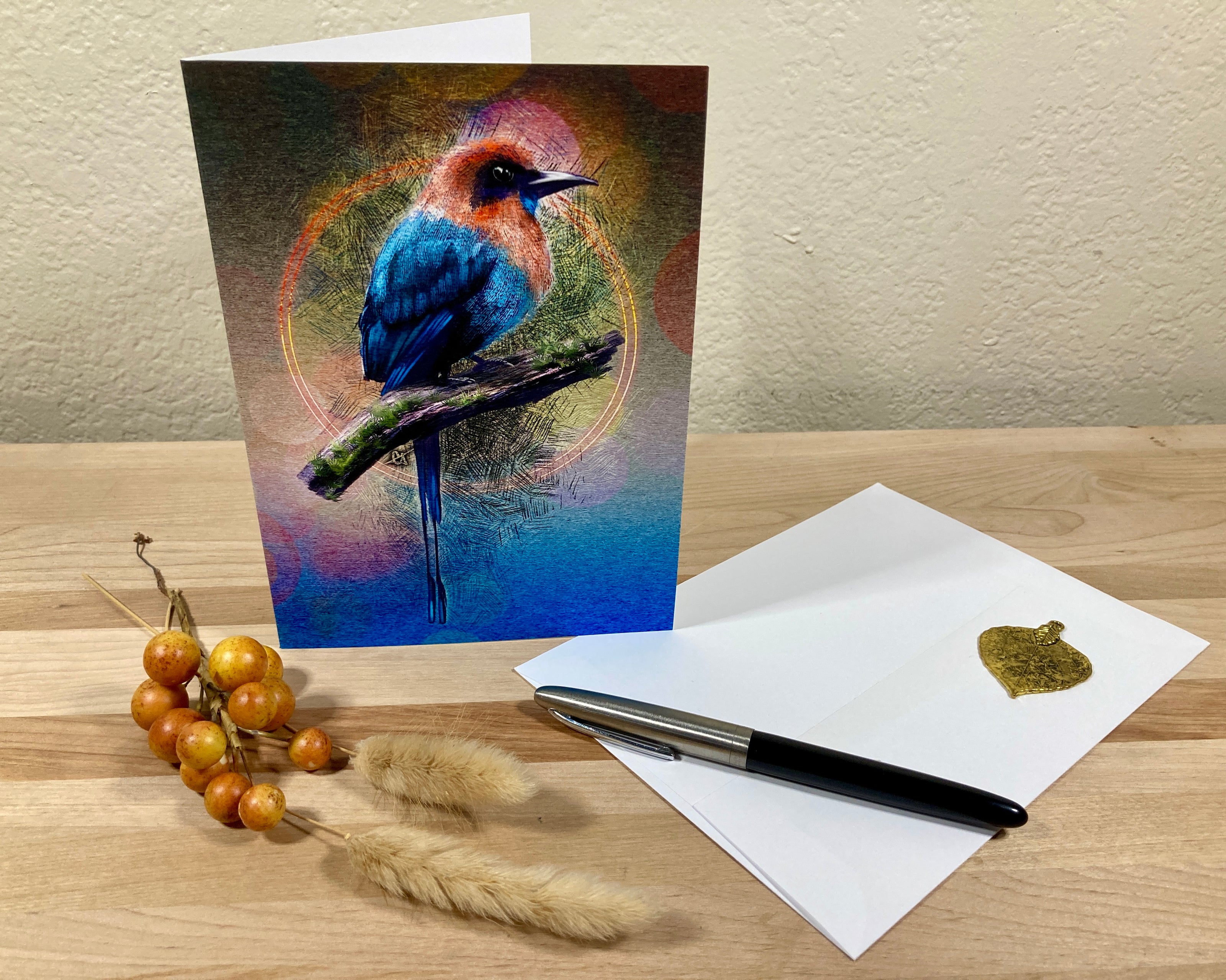 Greeting card with a colorful bird design on a wooden surface with a pen and envelope.