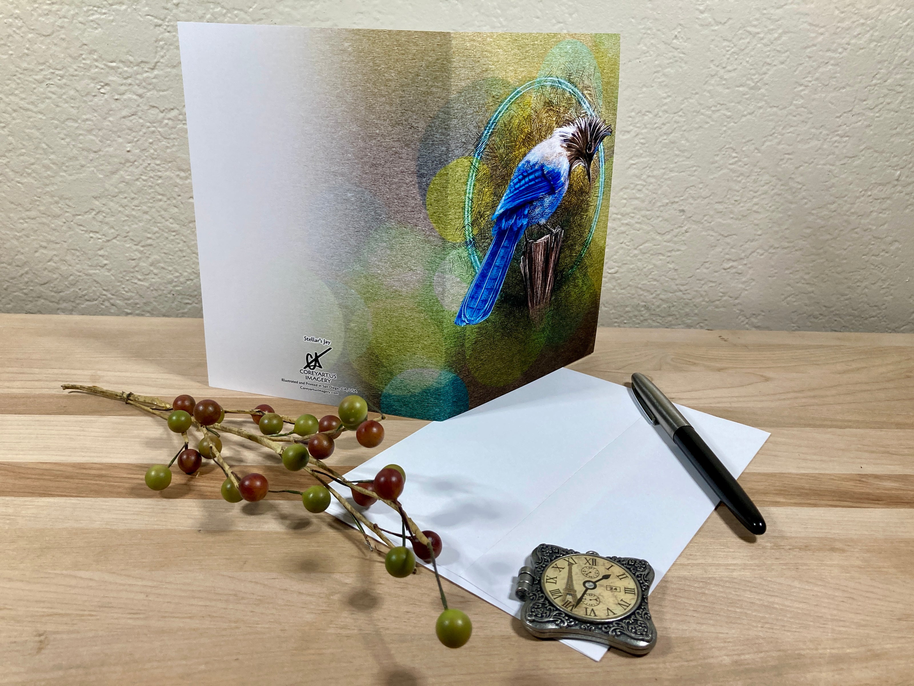 Greeting card with a blue bird illustration on a wooden surface with stationery items.