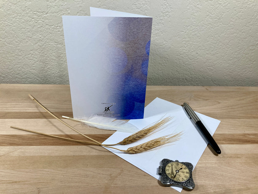 Greeting card, pen, and decorative items on a wooden surface with a neutral background