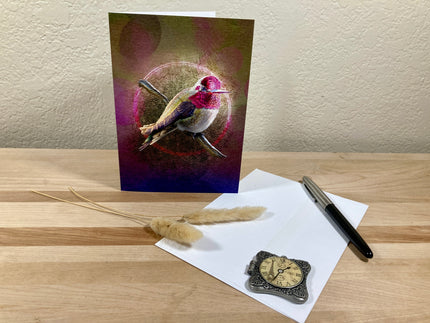Greeting card with a colorful bird design on a wooden surface with a pen and decorative stone.