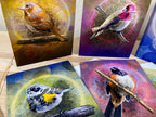 Four greeting cards with bird illustrations on a wooden surface