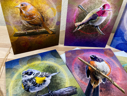Four greeting cards with bird illustrations on a wooden surface