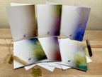 Backside of six greeting cards with artistic designs on a wooden surface