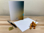 Greeting card, pen, and decorative items on a wooden surface with a neutral background