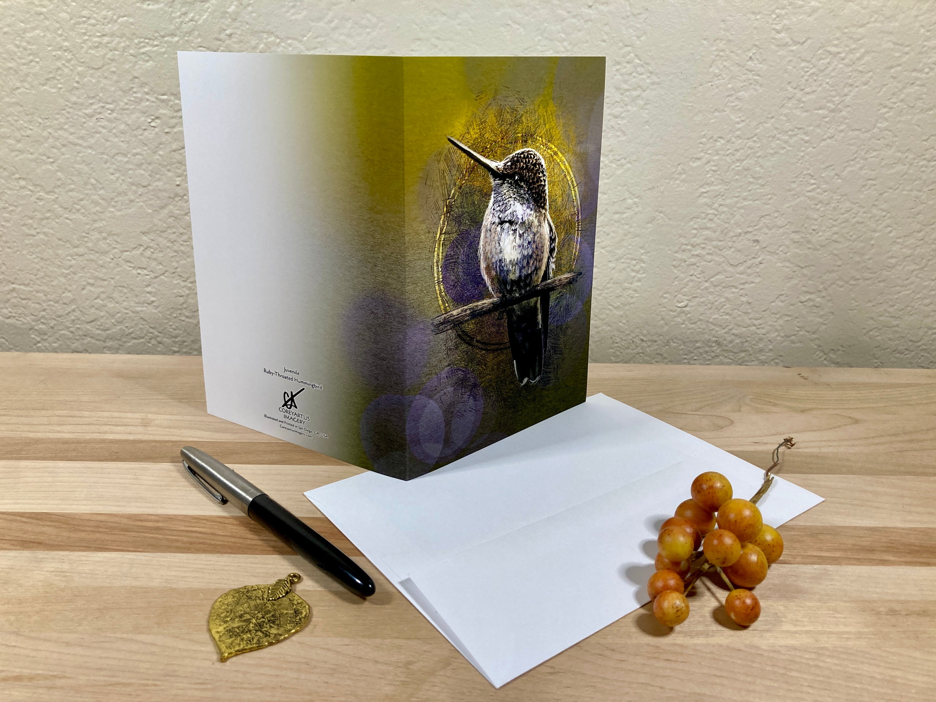 Greeting card with a bird design on a wooden surface with an envelope and pen.