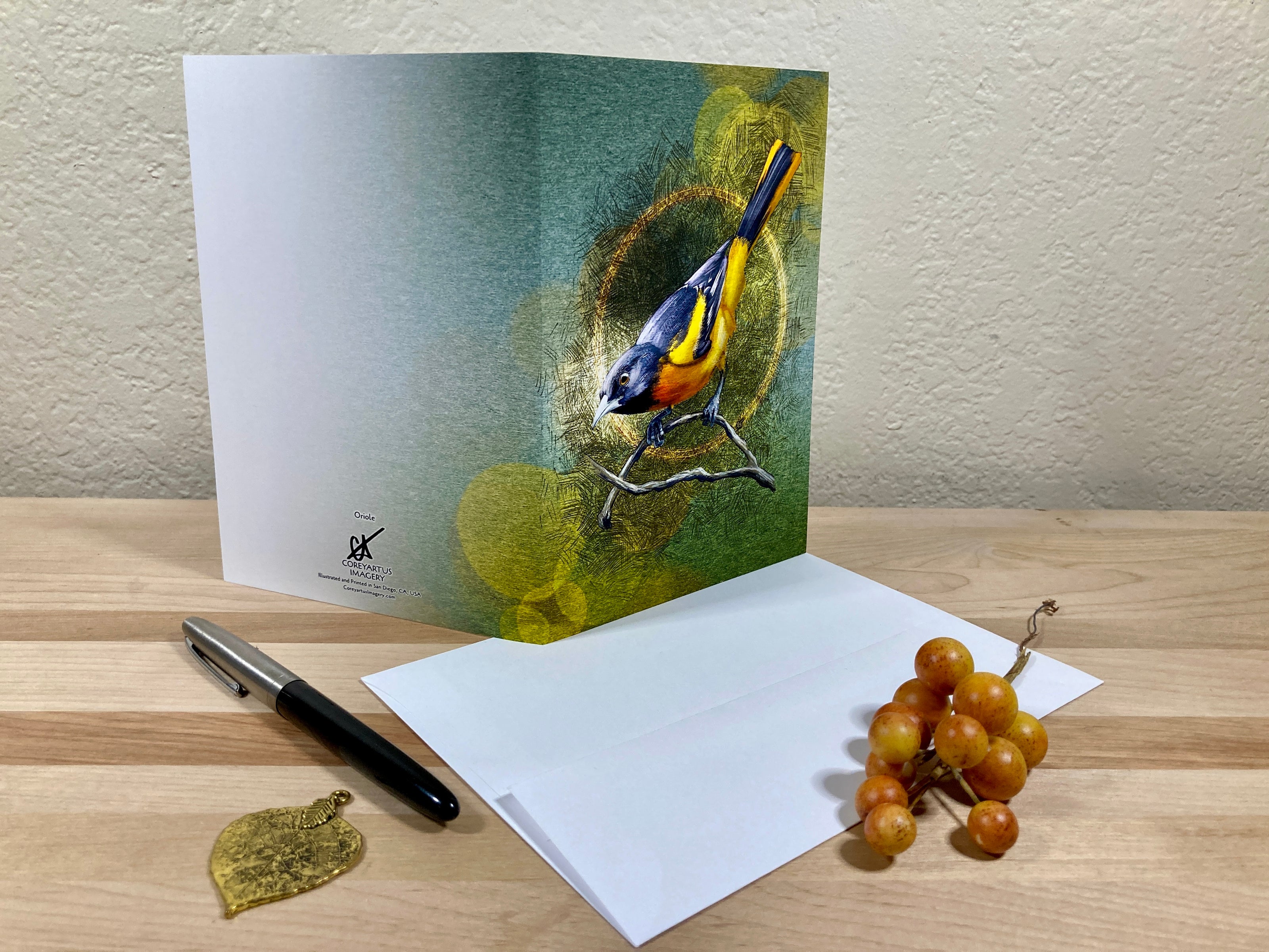 Greeting card with a bird illustration on a wooden surface with a pen and grapes.