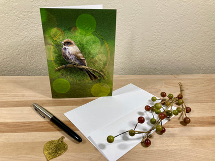 Greeting card with a bird design on a wooden surface with an envelope and pen.