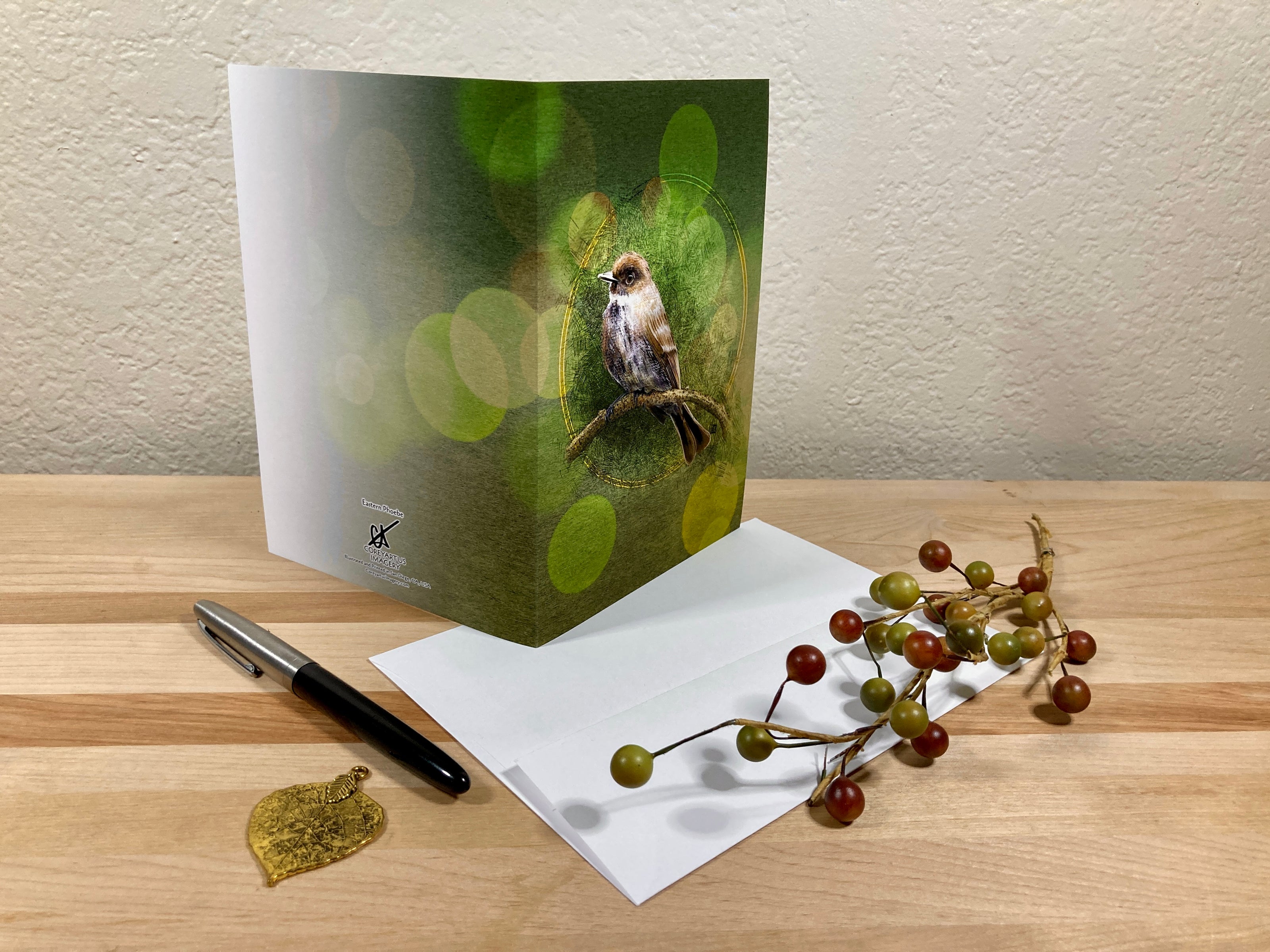 Greeting card with a bird design on a wooden surface with an envelope and pen.