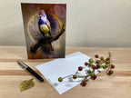 Greeting card with a bird design on a wooden surface with a pen and decorative branch.