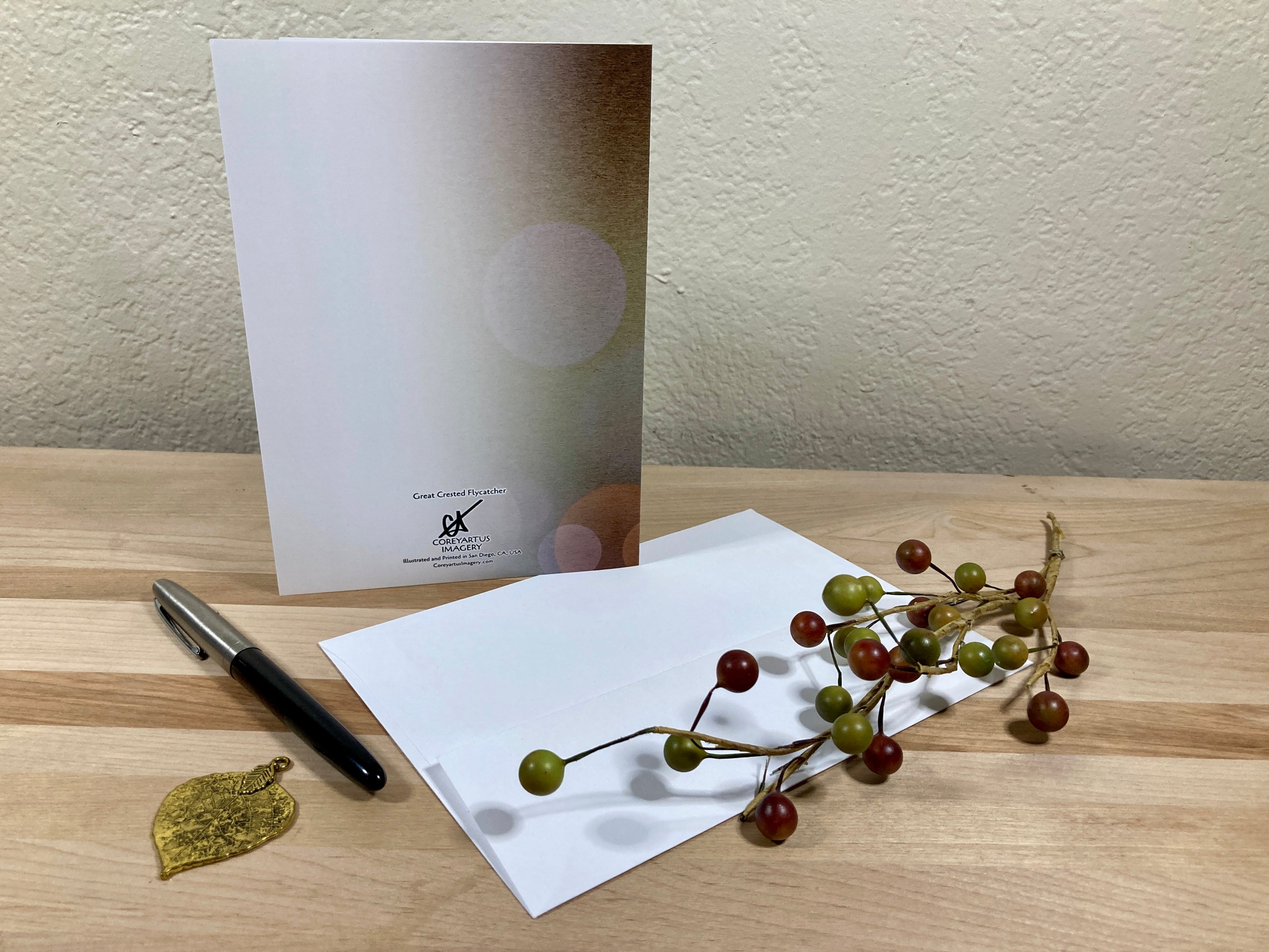 White card with a pen and decorative branch on a wooden surface