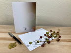 White card with a pen and decorative branch on a wooden surface
