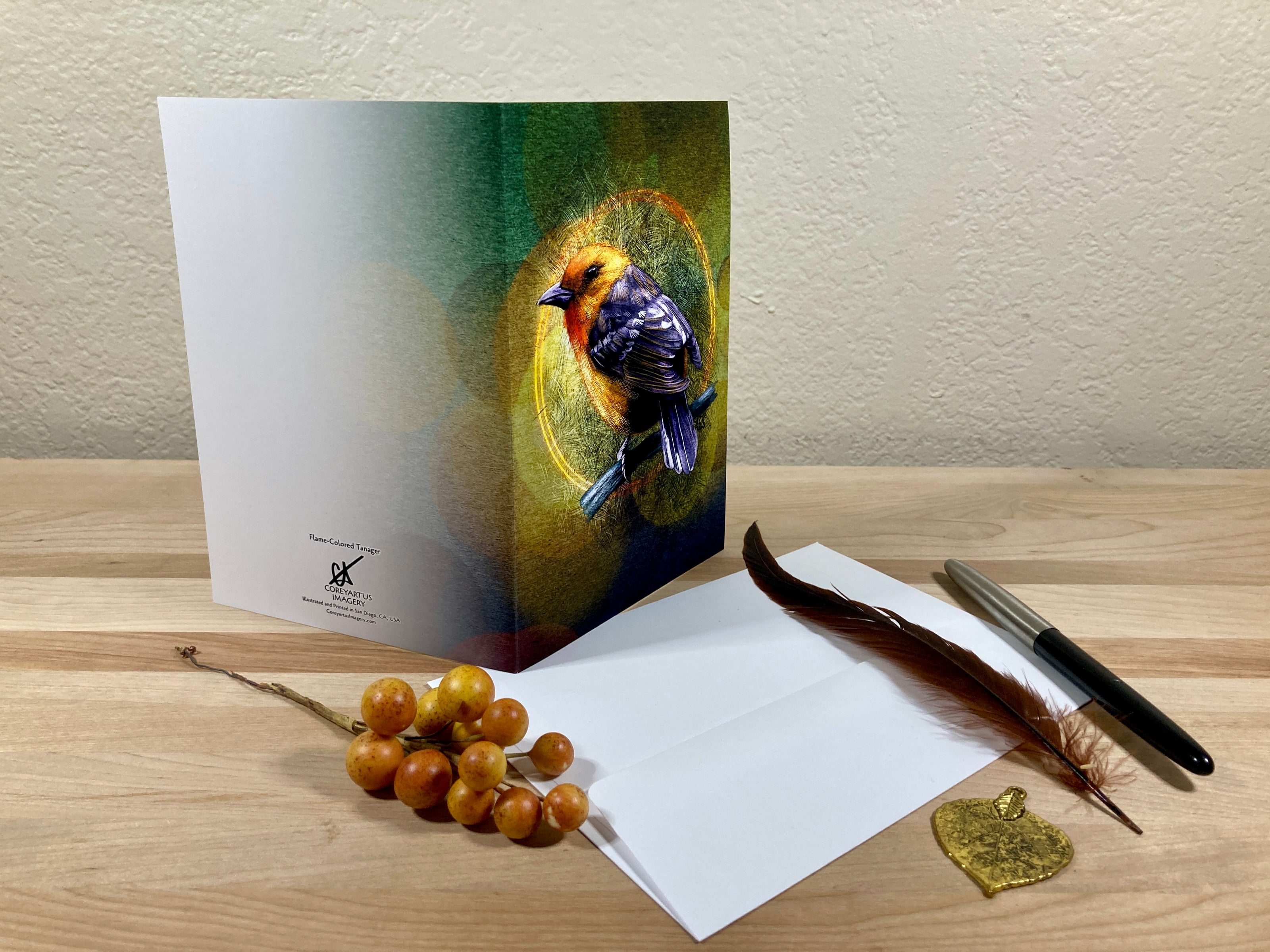 Greeting card with bird illustration on a wooden surface with envelope and pen.