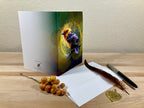 Greeting card with bird illustration on a wooden surface with envelope and pen.