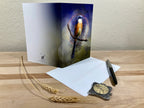 Greeting card with a bird design on a wooden surface with an envelope and pen.