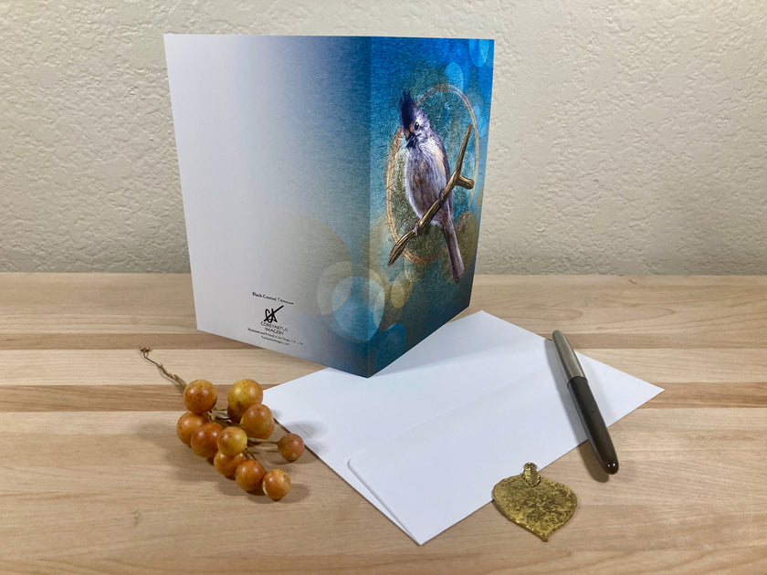 Greeting card with bird illustration on a wooden surface with envelope and pen.