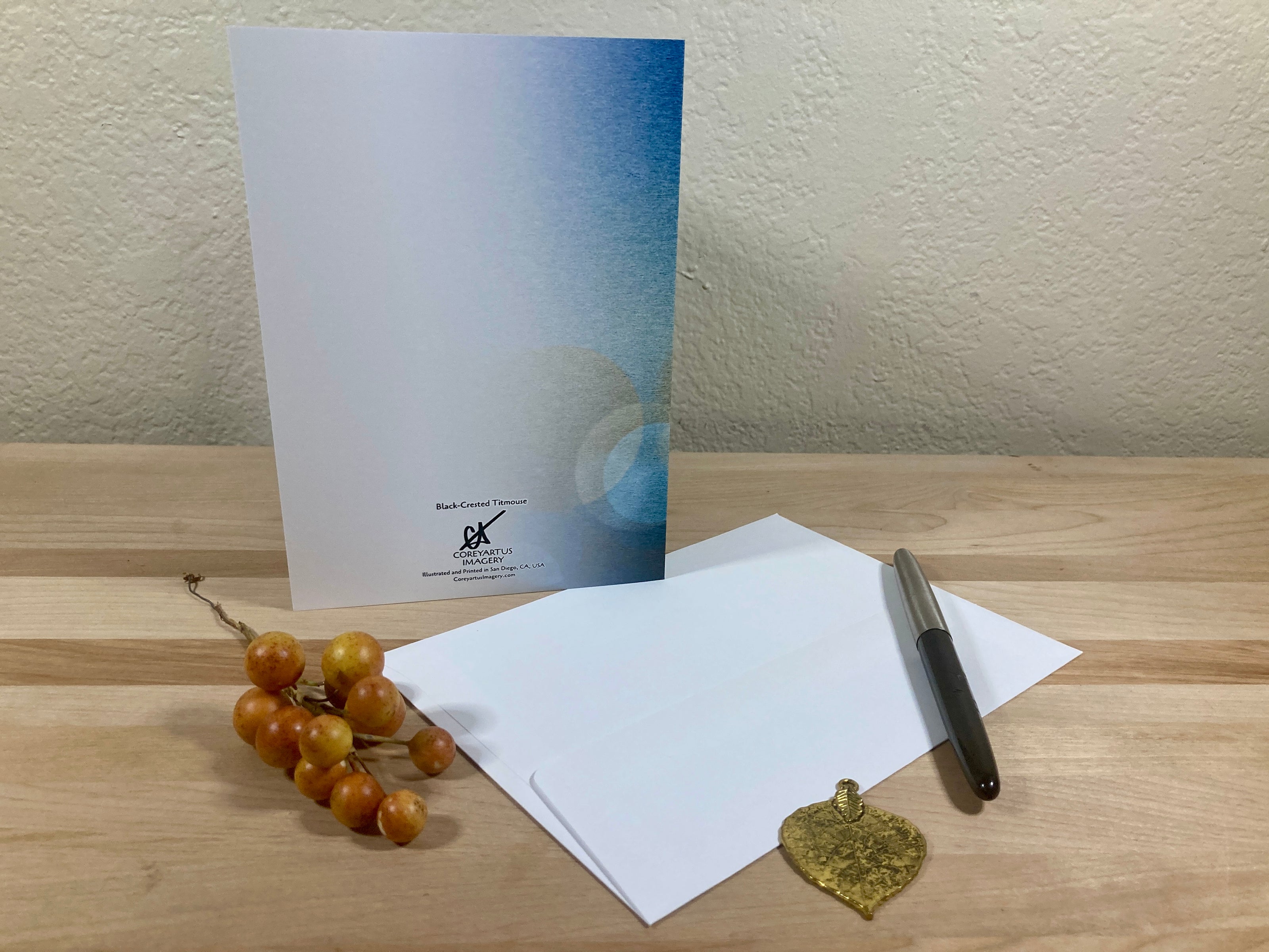 White card with a blue gradient and visible branding on a wooden surface with berries and a pen.