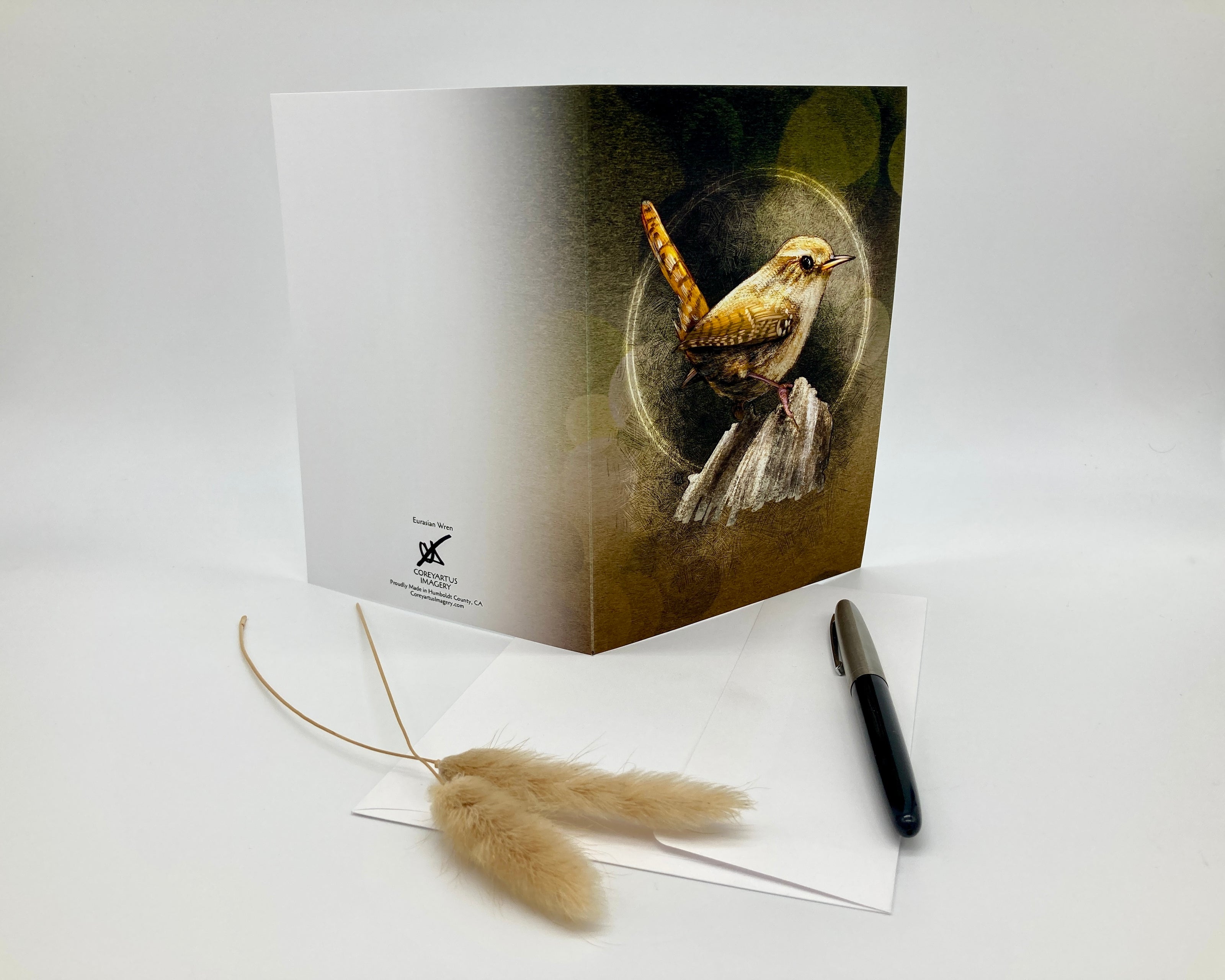 Greeting card with a bird design on a white surface with a pen and decorative item.