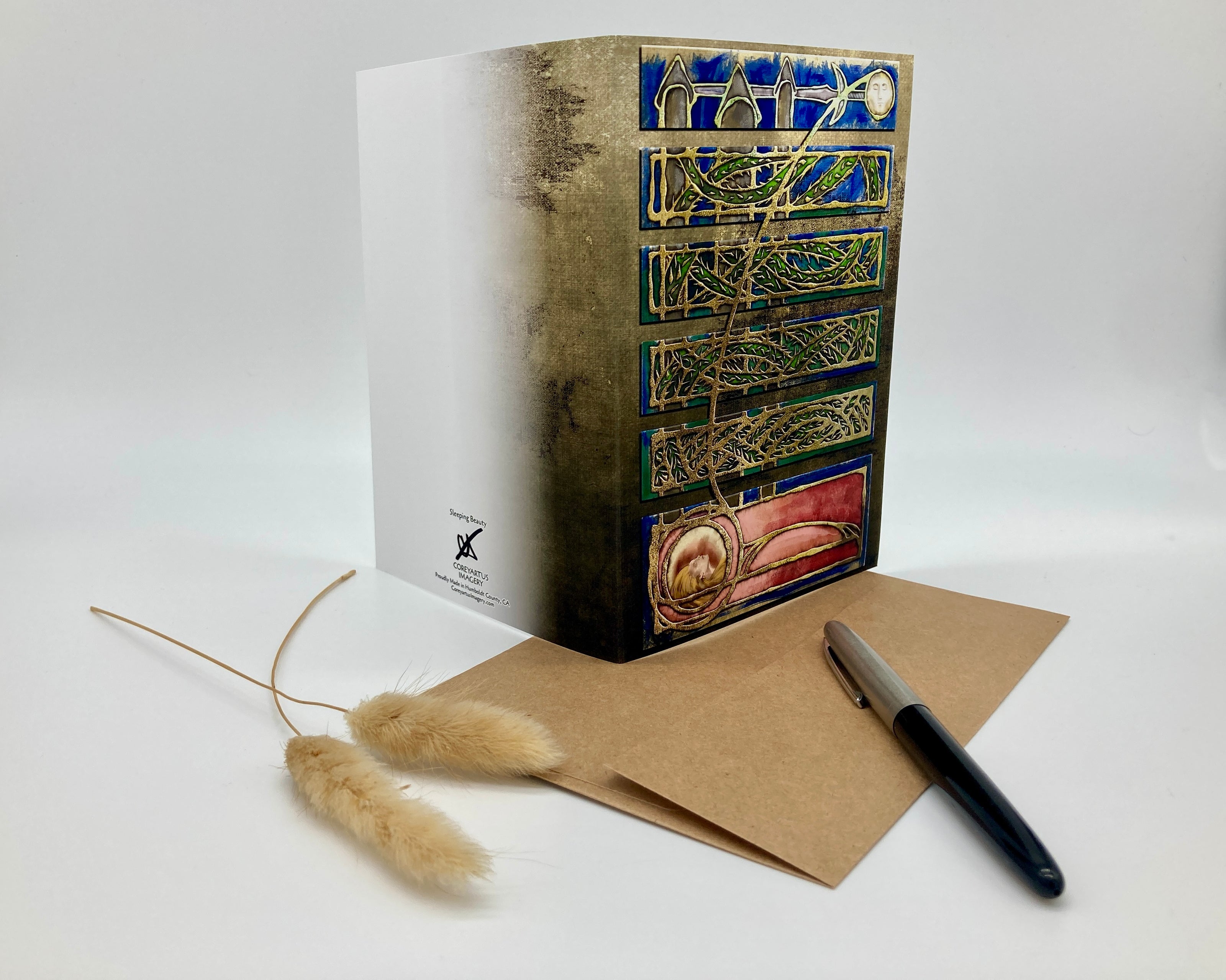 Decorative box with intricate designs, a pen, and a card on a white background