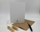 White greeting card with brown envelope and pen on a white background
