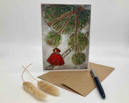 Greeting card with nature-themed design featuring a person in a red coat and branches, accompanied by a pen and envelope on a white background.