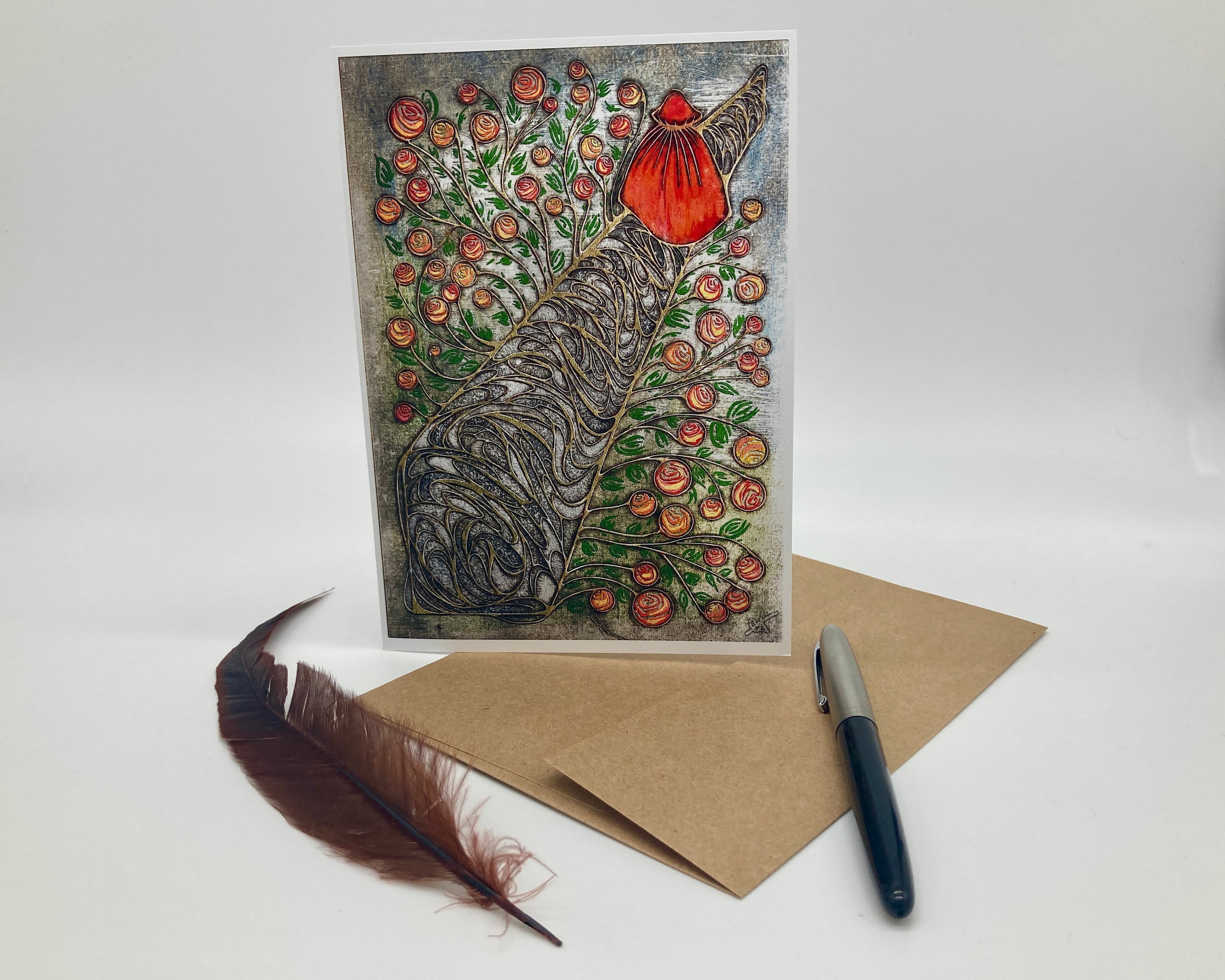 Greeting card with artistic design of a deer and flowers, accompanied by a feather and pen on a white background.