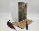 Greeting card with artistic design, feather, and pen on a white background