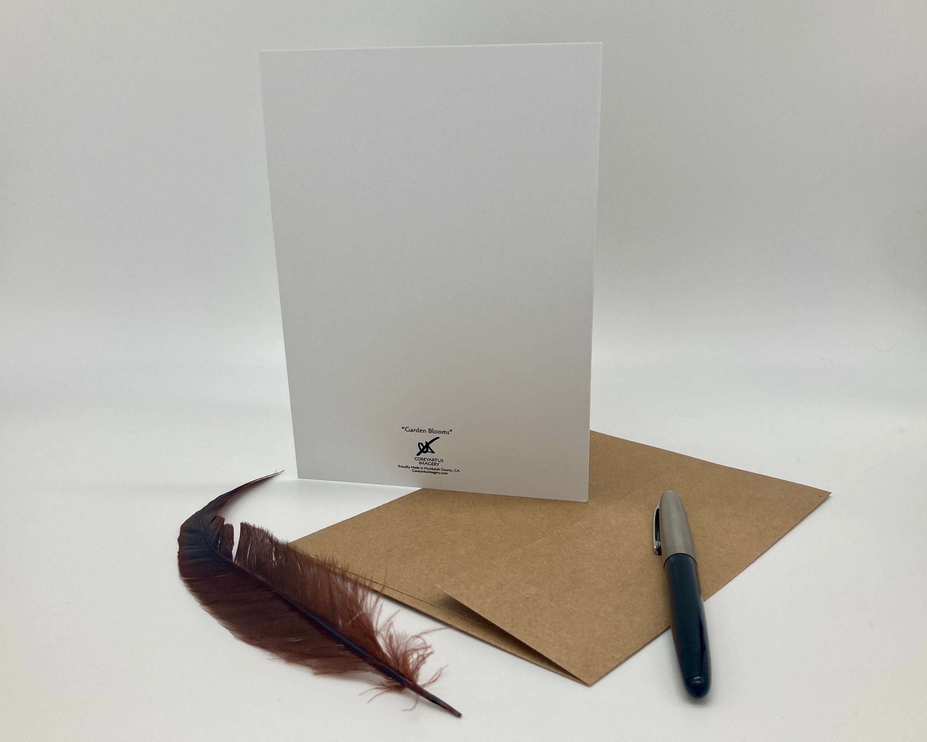White card with black text, brown envelope, feather, and pen on a white background