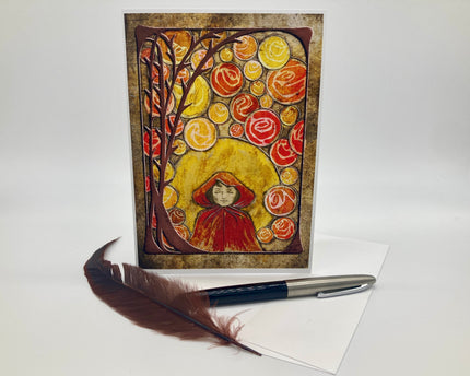 Artistic greeting card with a tree and floral design, accompanied by a pen and feather on a white background.