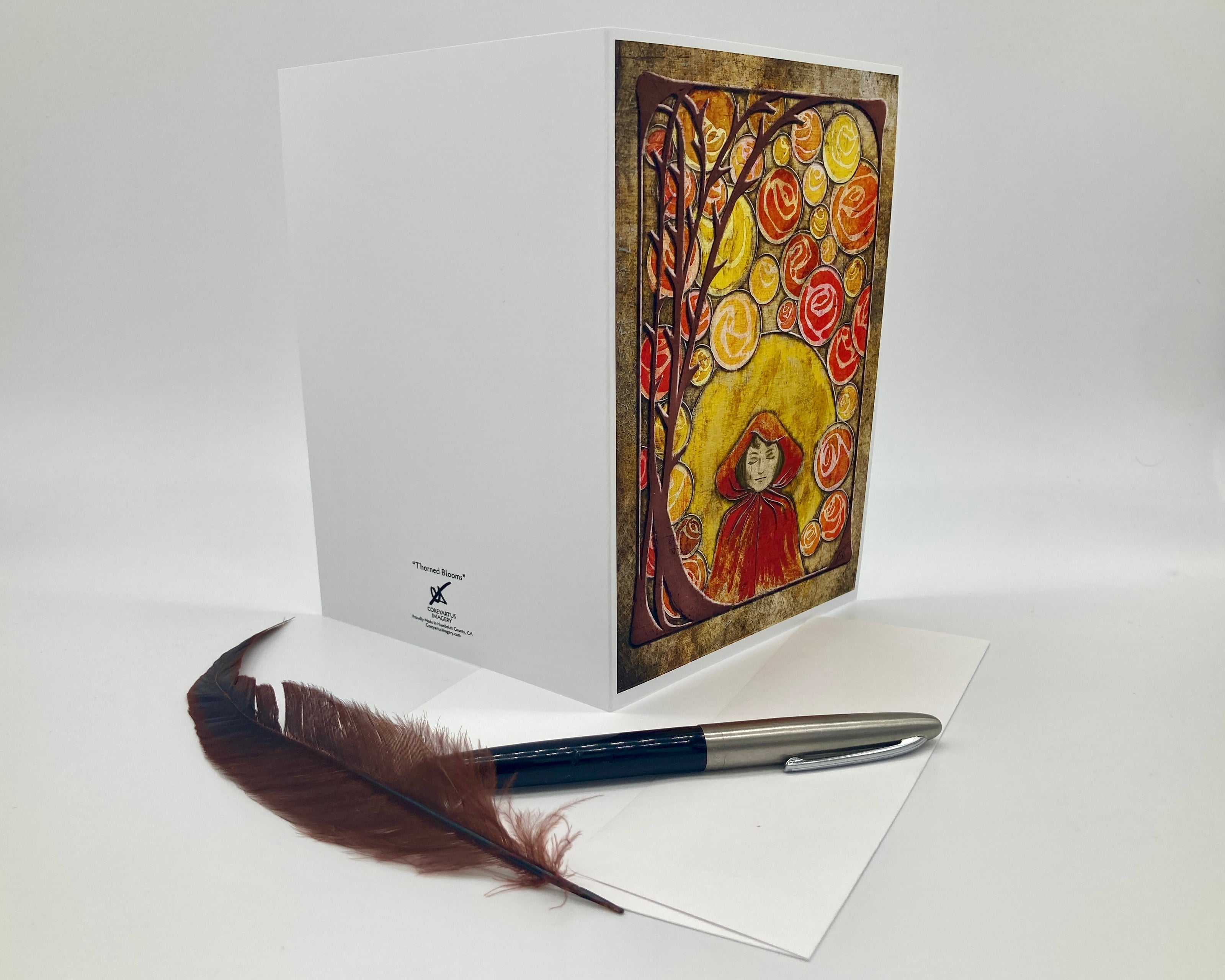 Greeting card with artistic design of a woman and tree, feather pen, and white envelope on a white background